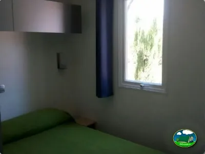 Mobil-home interior con cama y ventana del Camping Parque Tropical, Estepona (Málaga)