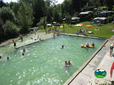 Piscina con vistas al entorno natural, llena de bañistas y actividades del Camping Wydeli, Brenzikofen (Berna)
