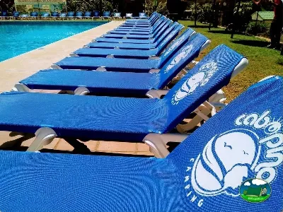 Piscina con hamacas azules y zona de césped del Camping Cabopino, Marbella (Málaga)