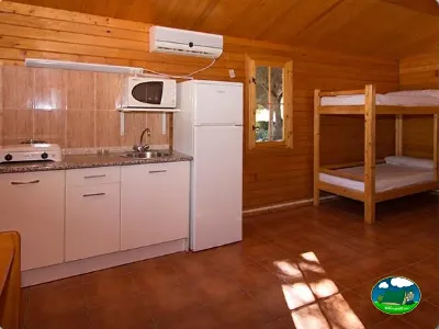 Cabaña interior con cocina equipada y literas de madera del Camping Cabopino, Marbella (Málaga)