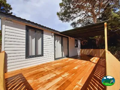 Mobil-home con terraza de madera y sombrilla del Camping Cabopino, Marbella (Málaga)