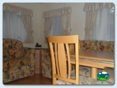 Interior de mobil-home con zona de estar y cortinas del Camping Valle Niza Playa, Benajarafe (Málaga)