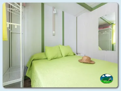 Mobil-home interior con cama doble y decoración verde del Camping El Pino, Urbanización Torrox Park (Málaga)
