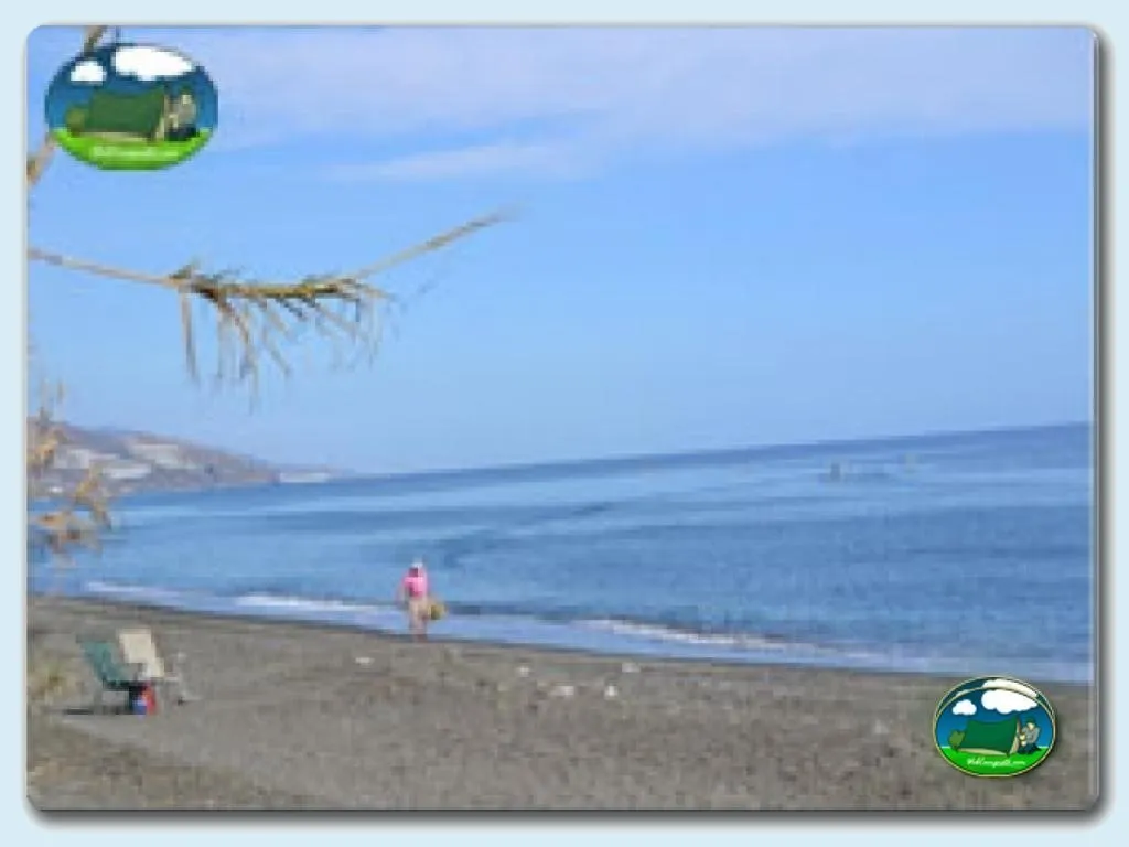 Playa junto al mar con bañistas y vista costera del Camping Castillo de Baños, Castillo de Baños (Granada)