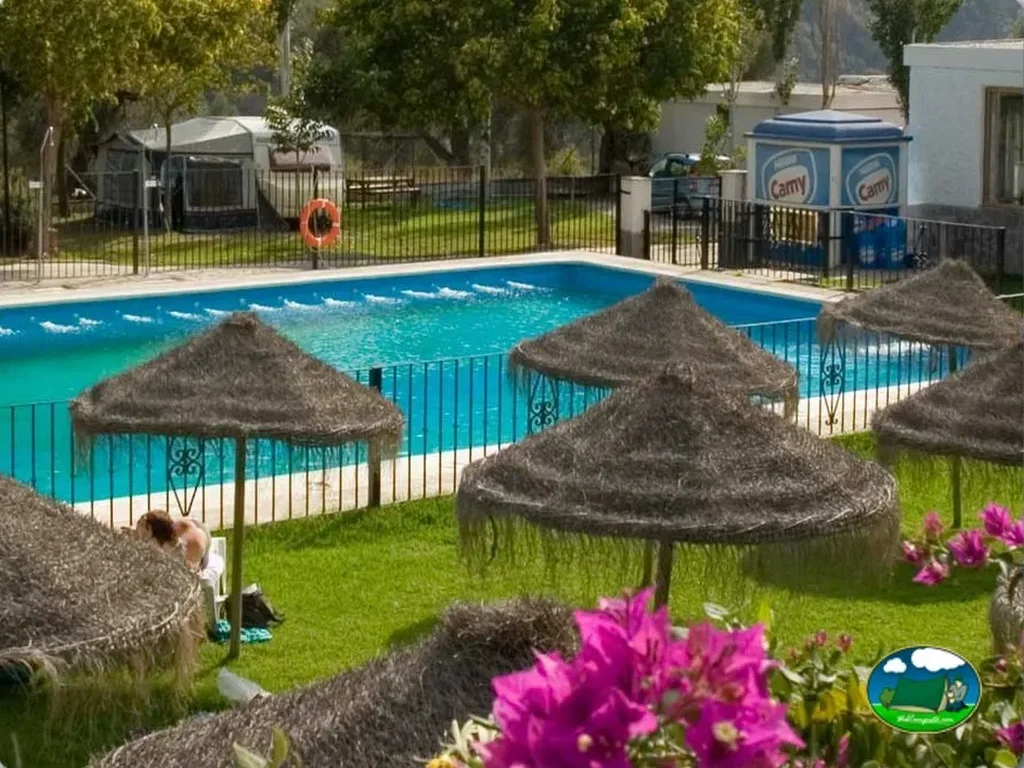 Piscina con sombrillas y jardín del Camping Orgiva, Órgiva (Granada)