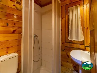 Baño interior de cabaña de madera con ducha y lavabo del Camping Las Lomas, Güejar Sierra (Granada)