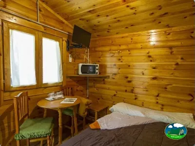 Cabaña de madera interior con cama y televisión del Camping Las Lomas, Güejar Sierra (Granada)