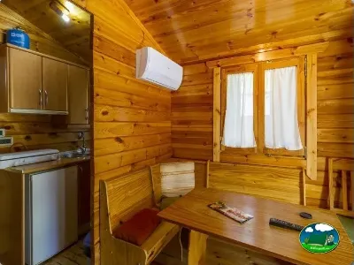 Cabaña interior con cocina, mesa y aire acondicionado del Camping Las Lomas, Güejar Sierra (Granada)