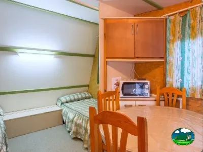 Mobil-home interior con cama y zona de estar del Camping Las Lomas, Güejar Sierra (Granada)