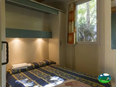 Mobil-home interior con cama doble y vistas al bosque del Camping Las Lomas, Güejar Sierra (Granada)