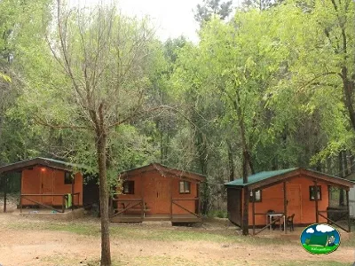 Cabaña roja entre árboles en parcela arbolada del Camping Puente de las Herrerías, Cazorla (Jaén)