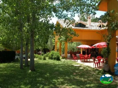 Restaurante con sombrillas rojas y zona de estar arbolada del Camping Puente de las Herrerías, Cazorla (Jaén)