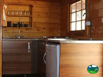 Cocina de glamping con madera, equipada con fogones y refrigerador del Camping Puente de las Herrerías, Cazorla (Jaén)