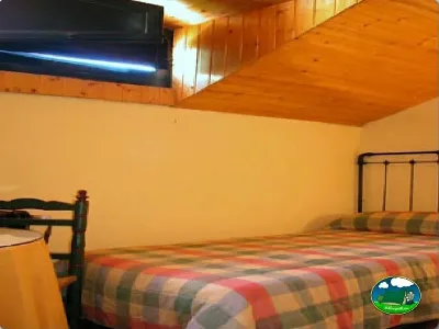 Cabaña interior con cama y techo de madera del Camping Puente de las Herrerías, Cazorla (Jaén)