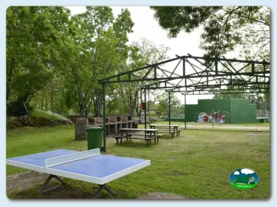Parque infantil con mesa de ping pong y zona de juegos bajo pérgola del Camping El Pinajarro, Hervás (Cáceres)