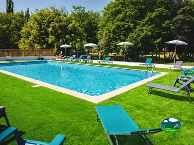 Piscina rodeada de árboles del Camping d'Auberoche, LE CHANGE (Dordoña)