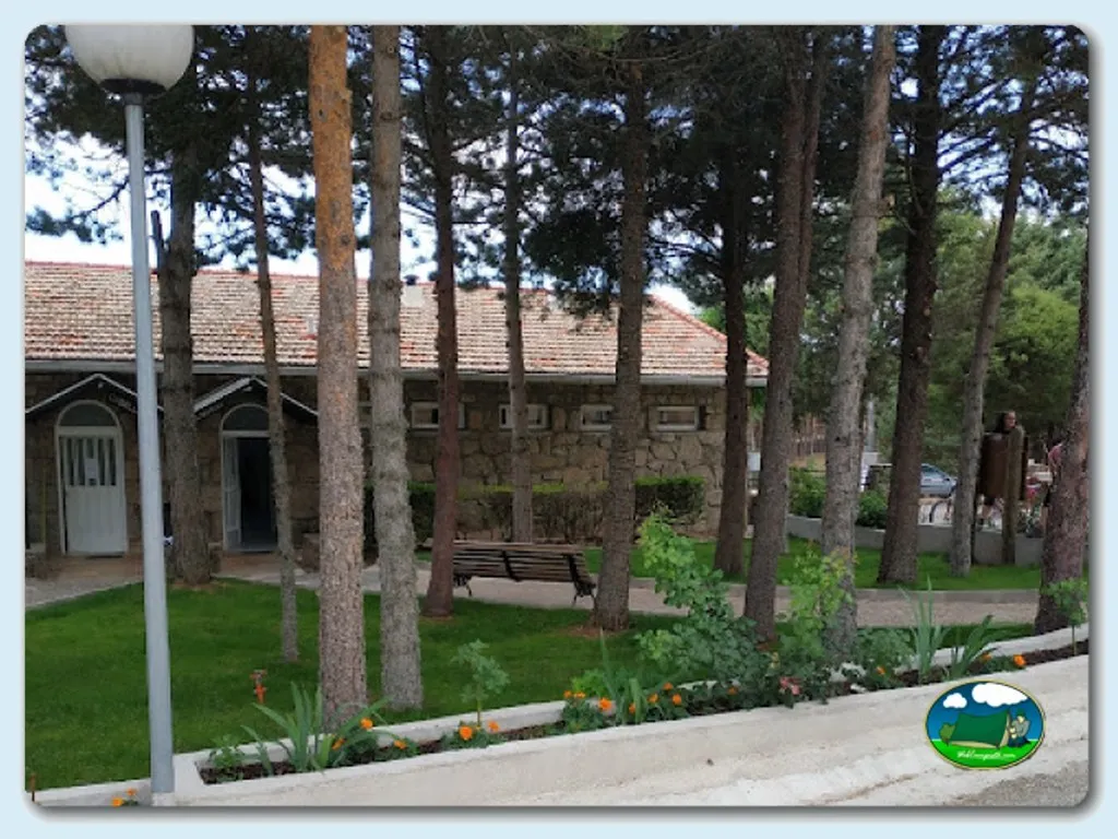Parcela con árboles y edificios de piedra del Camping La Nava, Peguerinos (Ávila)