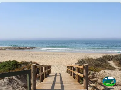 Playa junto al mar con pasarela de madera a la arena del Camping Valbom, Sesimbra (Setúbal)
