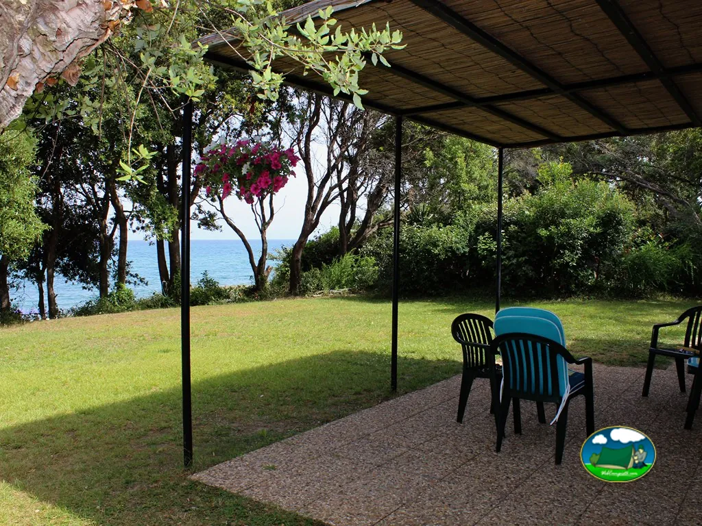 Parcela ajardinada con mesa frente al mar de Camping naturiste Corsica Natura, Linguizzetta
