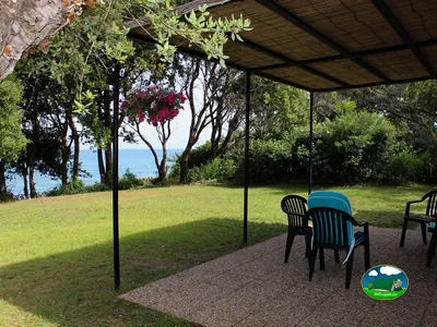 Parcela ajardinada con mesa frente al mar de Camping naturiste Corsica Natura, Linguizzetta
