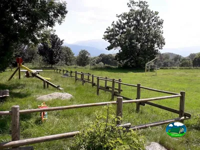 zona infantil con tobogán y columpios en el camping, con las montañas de fondo