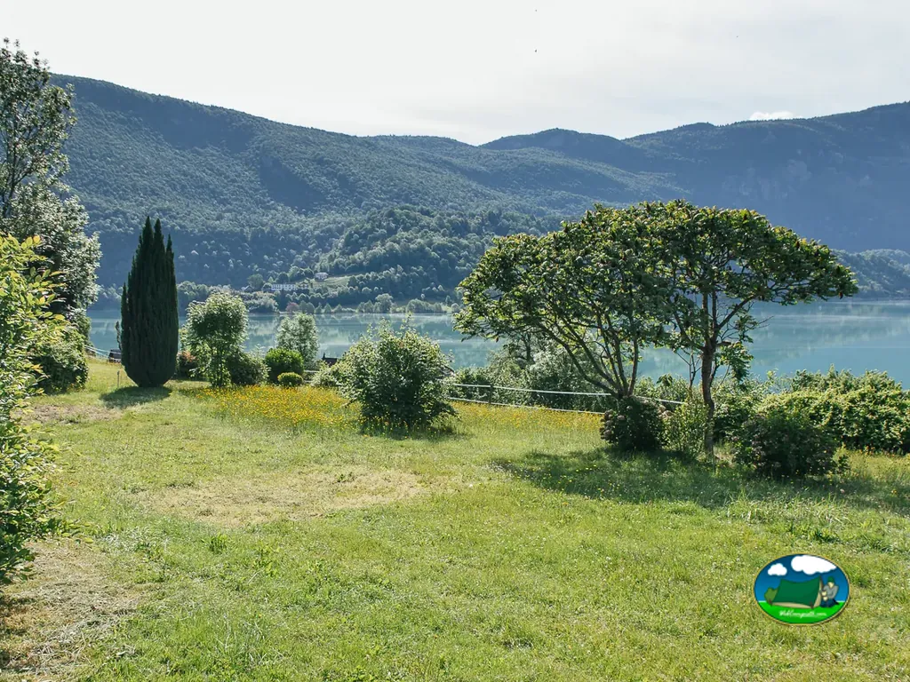 césped del camping con vistas al lago de Aiguebelette y montañas boscosas