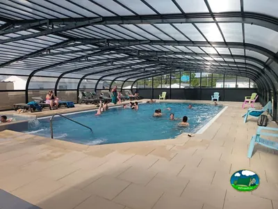 piscina cubierta del camping con bañistas y tumbonas, mobil-homes al fondo