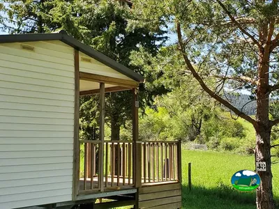 mobil-home con terraza de madera entre pinos en el camping