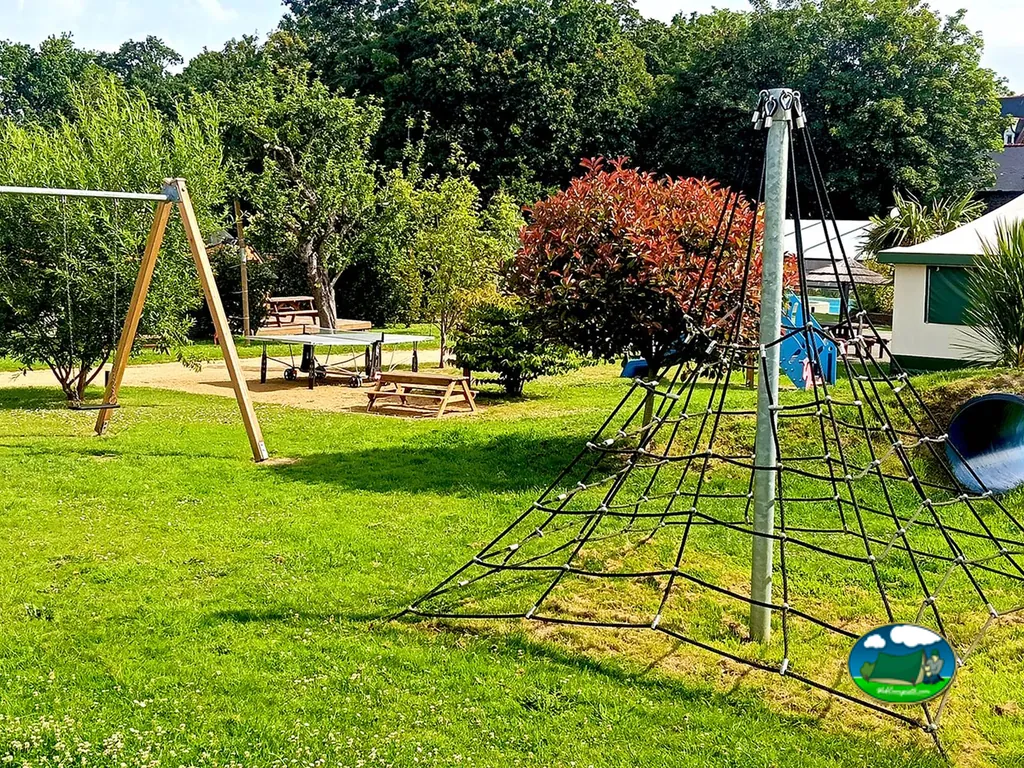 zona de juegos infantiles con columpio, red de escalada y mesas de picnic en el camping