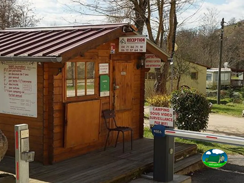 caseta de recepción de madera con tarifas y barrera de acceso en la entrada del camping