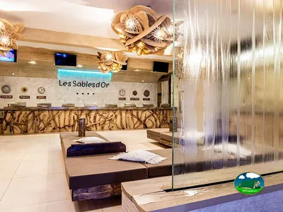 Recepción interior del camping con decoración de madera, luces cálidas y una pared de agua de cristal.