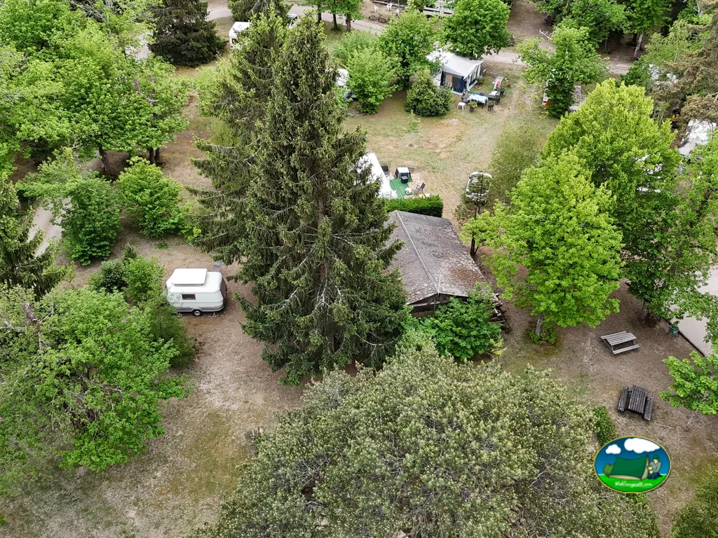 vista aérea de las parcelas arboladas del camping con una caravana y una cabaña en Saint-Cyr-en-Val
