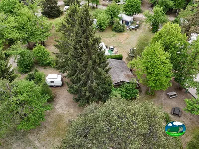 vista aérea de las parcelas arboladas del camping con una caravana y una cabaña en Saint-Cyr-en-Val
