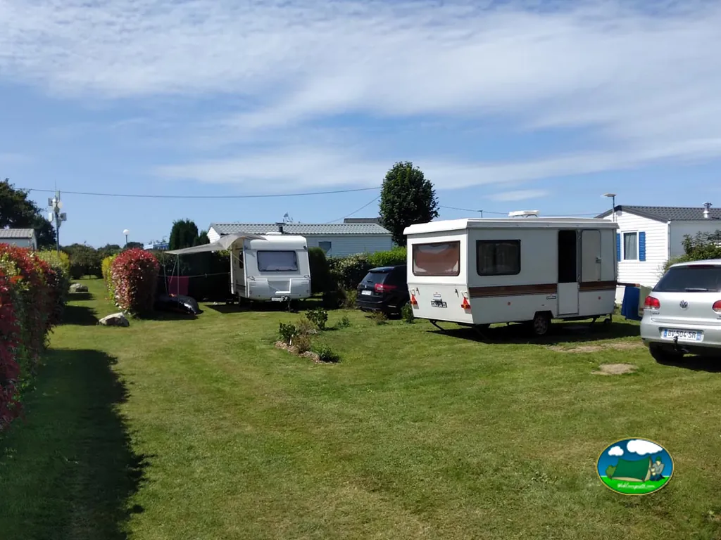 parcelas del camping con caravanas, coches aparcados y setos floridos