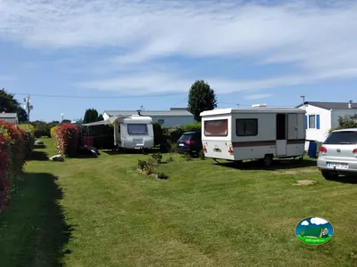 parcelas del camping con caravanas, coches aparcados y setos floridos