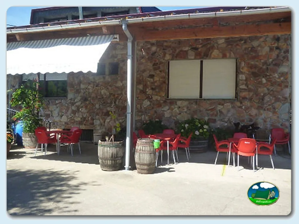 Restaurante con terraza y sillas rojas del Camping Rivera del Cúa, Vega de Espinareda (León)