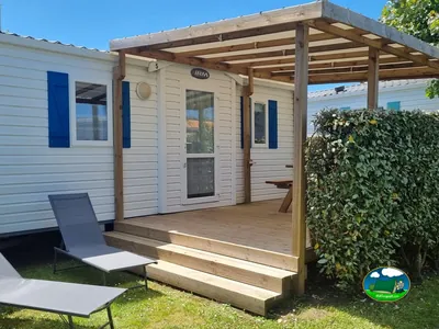 mobil-home con porche de madera cubierto y tumbonas en Le Grand-Village-Plage