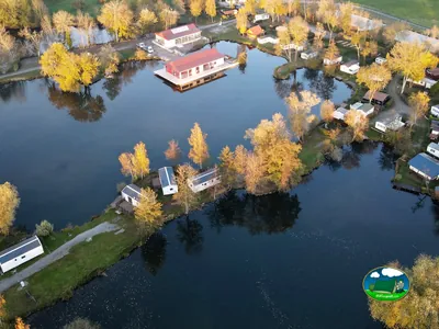 vista aérea del camping junto a un lago con una cabaña flotante de tejado rojo entre árboles otoñales en Sailly-le-Sec