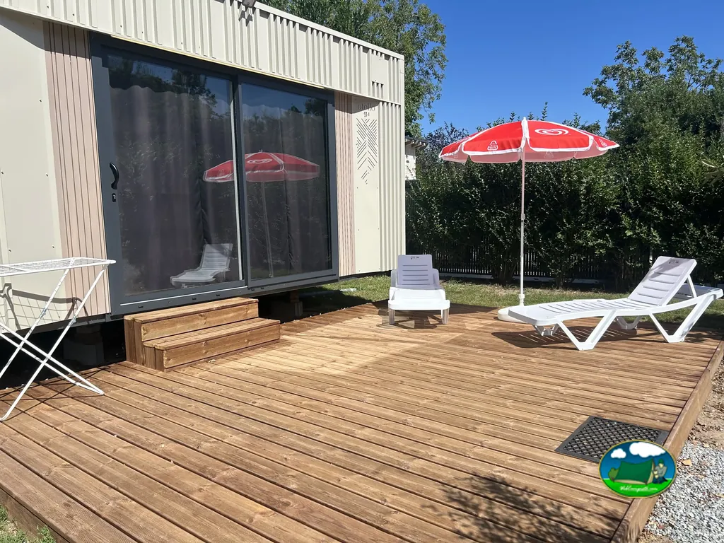 terraza de madera con tumbonas y sombrilla roja junto a un mobil-home en Verneuil-sur-Seine