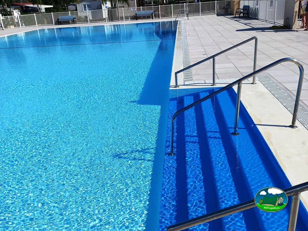 primer plano de una gran piscina azul con escalera metálica y solárium en Saint-Aygulf