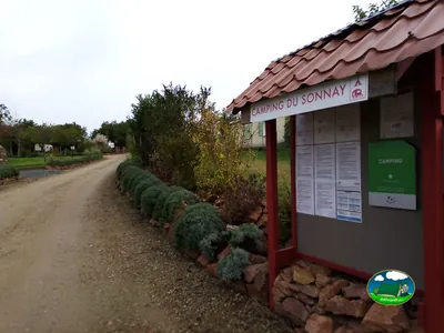 panel de entrada con el nombre y la normativa del Camping du Sonnay junto al camino de acceso