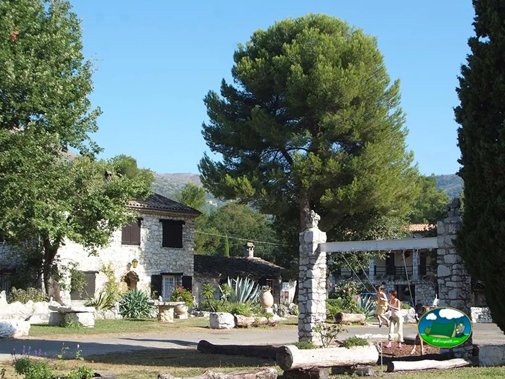 edificio de piedra de recepción del camping con jardín mediterráneo y pino frondoso en Vence