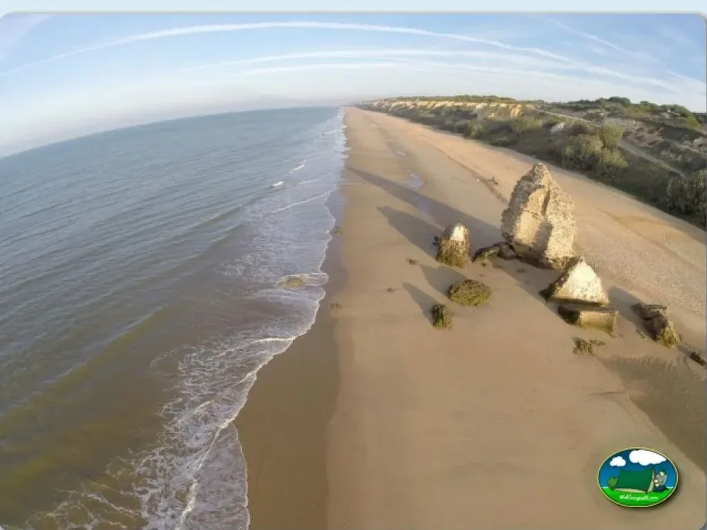 Playa junto al mar con acantilados y restos de estructuras históricas del Camping Doñana Playa, Matalascañas (Huelva)