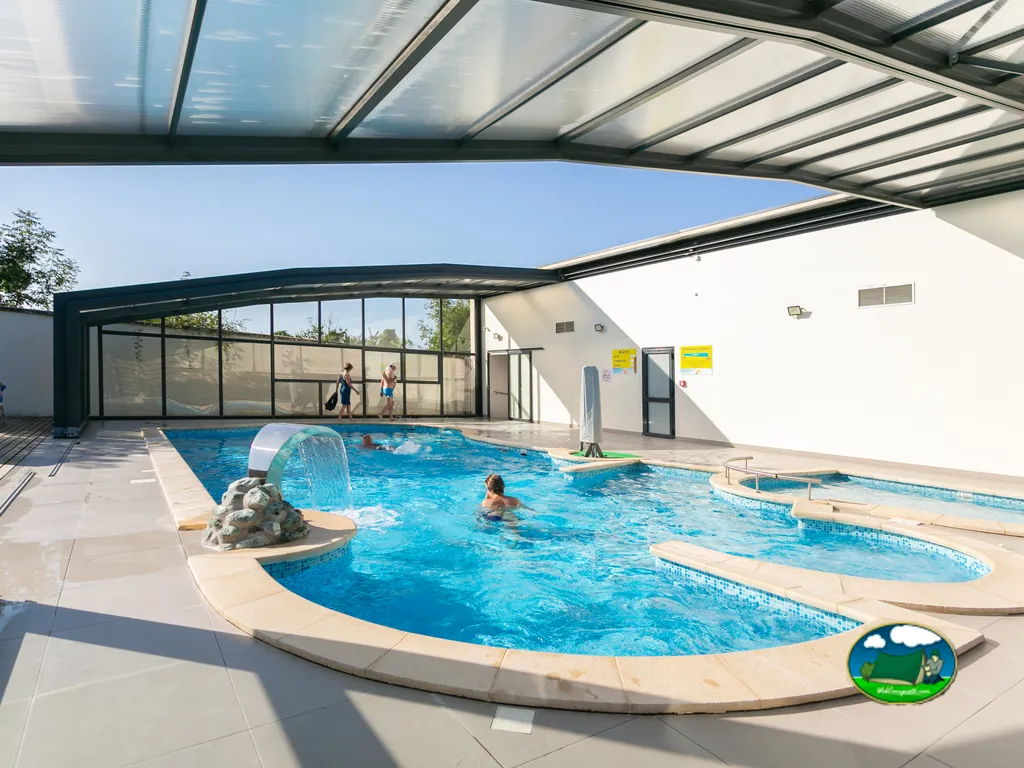 piscina cubierta del camping con bañistas y tobogán de agua en Villers-lès-Nancy