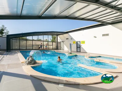 piscina cubierta del camping con bañistas y tobogán de agua en Villers-lès-Nancy