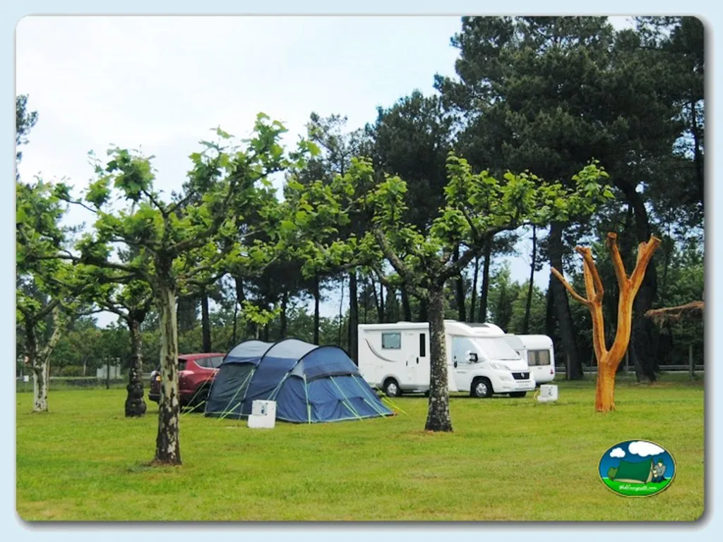 Parcela con tienda de acampada y mobil-home bajo árboles del Camping El Mesón, Guitiriz (Lugo)