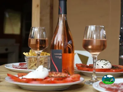 mesa con copas de vino rosado, patatas fritas y tomate con burrata en el restaurante del camping