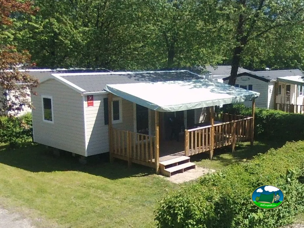 mobil-home con terraza de madera entre árboles en el camping de Saint-Pierre-d'Albigny