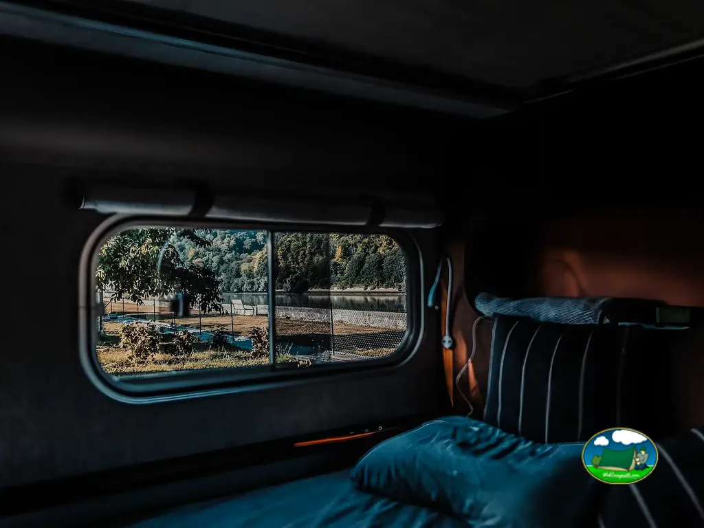 interior en penumbra de una caravana con vistas al río del camping en Jumièges