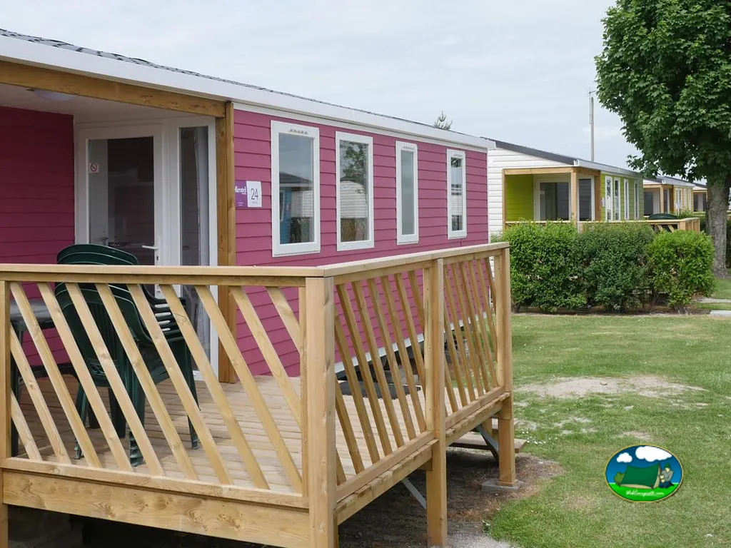 mobil-home rosa con terraza en una fila de alojamientos del camping en Fort-Mahon-Plage